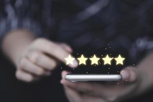 donna d'affari che utilizza smartphone con cinque stelle gialle luminose per il concetto di prodotto e servizio della recensione del cliente del cliente. foto