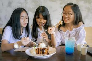 gruppo di adolescenti asiatici che mangiano uno spuntino dolce nel caffè foto