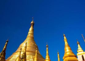 un gruppo di pagode dorate sotto il cielo blu del Myanmar foto