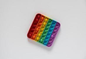 giocattolo colorato antistress per bambini pop it. quadrato con colori arcobaleno isolato su sfondo bianco. foto
