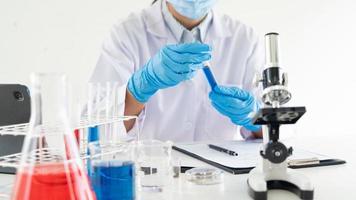 giovane scienziato asiatico che lavora guardando attraverso un microscopio facendo ricerche per analizzare un campione di esperimenti in un laboratorio forense.