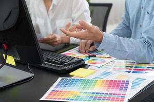 team di grafici che lavora al web design utilizzando campioni di colore modifica grafica utilizzando tablet e uno stilo alle scrivanie in ufficio creativo