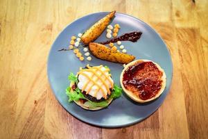 hamburger di manzo fatto in casa con spicchi di patate su piatto blu guarnire con senape, maionese, barbecue e salsa di formaggio. vista dall'alto. foto