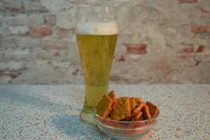 un bicchiere di birra chiara fresca con crostini o biscotti foto