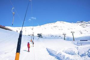 sciatori all'ascensore di resistenza sulla montagna delle alpi contro il cielo foto