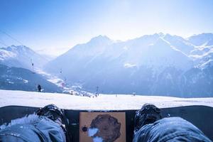 gambe dell'uomo snowboard sul paesaggio montano innevato foto