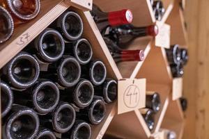 varietà di vino in bottiglie di vetro su scaffalature di legno con numeri nel supermercato foto
