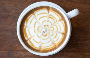 primo piano di arte del caffè latte con caramello sulla superficie dell'acqua che serve sul tavolo di legno. foto