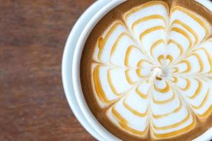 primo piano di arte del caffè latte con caramello sulla superficie dell'acqua che serve sul tavolo di legno. foto