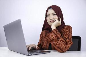 la giovane donna asiatica dell'islam è un aspetto serio con un gesto di pensiero mano sul viso sulla parte anteriore del laptop. foto