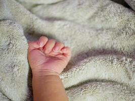 mano del bambino sulla coperta grigia. i neonati si sentono al sicuro e al caldo. messa a fuoco morbida selettiva. foto