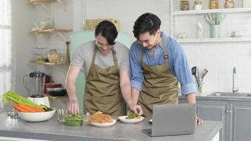 giovane coppia gay sorridente che cucina insieme in cucina a casa, lgbtq e concetto di diversità.