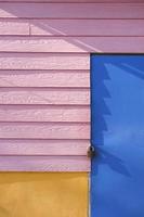 parte della porta prefabbricata blu e legno artificiale rosa con parete in cemento giallo del chiosco della strada del caffè vintage in cornice verticale foto