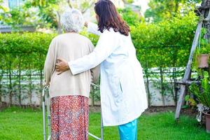 il medico aiuta la donna anziana asiatica con disabilità a piedi con il deambulatore nel parco, concetto medico. foto