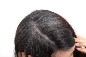 capelli brizzolati sulla testa di una donna su sfondo bianco. primo piano trama di capelli grigi. il concetto di primi capelli grigi foto