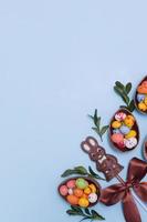 concetto di caccia di pasqua piatto con uova di cioccolato e coniglietto su sfondo blu. vista dall'alto copia spazio foto