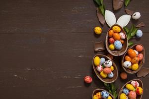 sfondo del concetto di caccia di pasqua con uova di cioccolato e coniglietto sullo spazio della copia del tavolo di legno. vista dall'alto foto