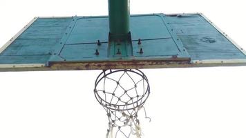 vista dal basso del vecchio canestro da basket verde scuro e della rete rotta con uno sfondo scuro del cielo mattutino nel campo sportivo pubblico. foto