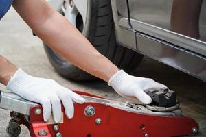 il meccanico usa il cric per sollevare l'auto per riparare la sospensione dell'auto. foto