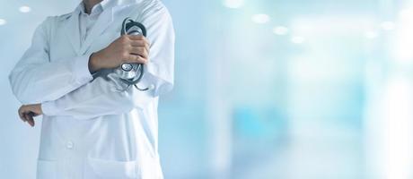 medico di medicina maschile con lo stetoscopio in mano in piedi con sicurezza sullo sfondo dell'ospedale