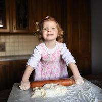 bambina sorridente che impasta la pasta foto