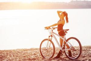 donna su una bicicletta vicino all'acqua foto