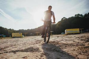 motociclista che guida lungo la spiaggia al tramonto foto