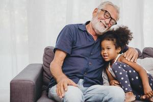 il nonno abbraccia l'amore dell'abbraccio per la nipote della bambina in una calda casa di famiglia. foto