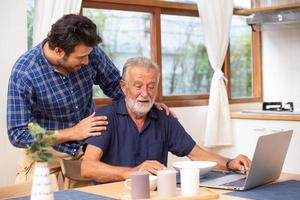 assistenza agli anziani a casa, buon mentore sano uomo anziano intelligente che usa il computer portatile resta al giovane. foto