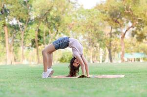 ragazze per metà thai-europee che si esercitano in ginnastica come parte del loro apprendimento al di fuori della scuola nel parco foto