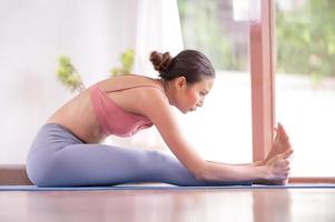 la meditazione e lo stretching delle donne asiatiche rilassano i muscoli facendo yoga nella stanza foto