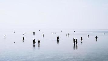 persone stagliate che camminano e nuotano in acque poco profonde foto