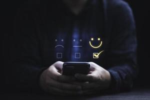 uomo d'affari che utilizza lo smartphone per selezionare l'icona della faccina sorridente per la valutazione del cliente e la soddisfazione del cliente dopo l'uso concetto di prodotto e servizio. foto