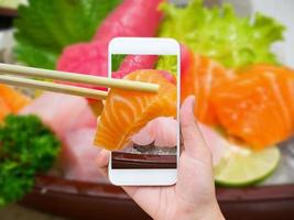 mano femminile che scatta foto del set di sushi sashimi