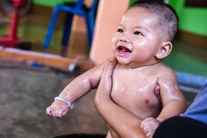 neonato sorridente felice facendo un bagno e guardando qualcuno con bellissimi occhi neri. foto
