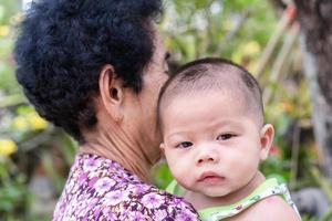 adorabile bambino che guarda l'obbiettivo con interesse sulla spalla della nonna. foto