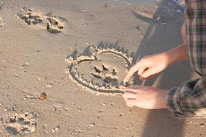 impronta del cane sulla sabbia bagnata e il cuore intorno ad esso foto