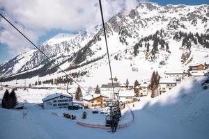 sciatori che guidano le seggiovie alla stazione sciistica durante la vacanza sugli sci contro le montagne foto