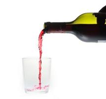 bottiglia di vino versando liquido in un bicchiere di vetro foto