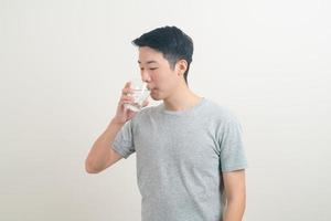 giovane uomo asiatico con un bicchiere d'acqua a portata di mano foto