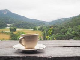 una tazza di caffè sulla tavola di legno con lo sfondo delle montagne foto