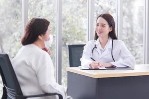 la donna anziana asiatica si consulta con il medico in merito al suo sintomo o problema di salute nella sala d'esame dell'ospedale. foto