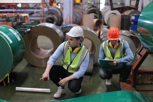 il caposquadra o il lavoratore del settore lavora presso il sito di fabbrica controlla la macchina o i prodotti in loco. ingegnere o tecnico che controlla materiale o macchina sull'impianto. industriale e di fabbrica. foto