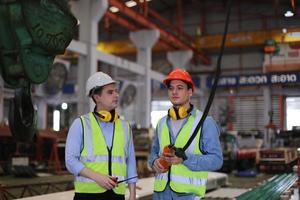 ingegnere industriale maschile che indossa un casco di sicurezza mentre si trova in una fabbrica industriale pesante. la manutenzione cercando di lavorare su macchinari industriali e controllare l'installazione del sistema di sicurezza in fabbrica. foto