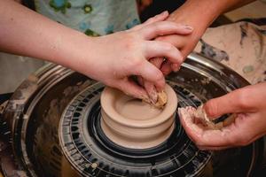 vasaio che lavora al tornio del vasaio con l'argilla. processo di produzione di stoviglie in ceramica nel laboratorio di ceramica. foto