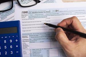 compilando i moduli fiscali 1040. us dichiarazione dei redditi individuali su una scrivania. foto