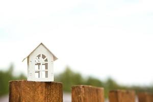 piccola figura di casa in legno bianco sul recinto con chiave per alloggi sullo sfondo dei cottage. costruzione, progettazione, progetto, trasloco in nuova casa, mutuo, affitto e acquisto di immobili. copia spazio foto