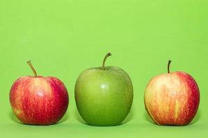 tre mele sono disposte su sfondo verde. un frutto nel mezzo colore verde eccezionale altro concetto minimo di cibo foto