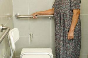 donna anziana asiatica paziente uso supporto WC in bagno, barra di sostegno di sicurezza corrimano, sicurezza in ospedale di cura. foto