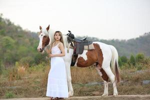 giovane donna con il suo cavallo nella luce del tramonto di sera. fotografia all'aperto con ragazza modella. umore dello stile di vita foto